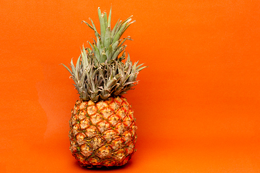 One single exotic tropical fruit over orange color background . Image made in studio