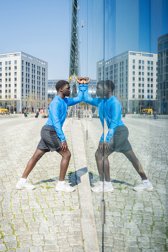 portrait of young sportsman reflecting in window pane in modern berlin