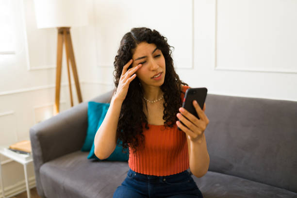istock Tired young woman using her phone with eye strain or irritation 1487827700