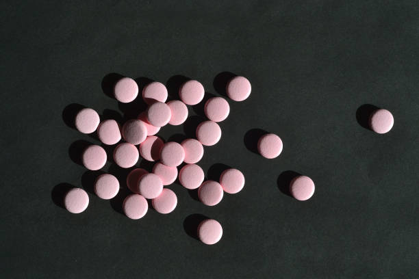 las píldoras rosadas se encuentran sobre un fondo negro - pink pill fotografías e imágenes de stock