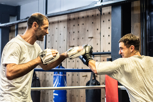 Young man training boxing with his trainer in the ring