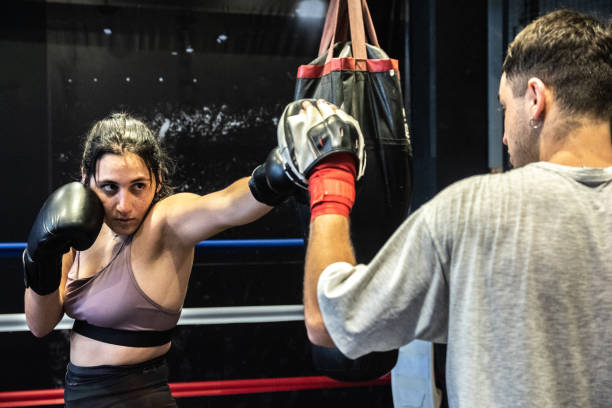 istock Young woman training boxing with her trainer in the ring 1487831839