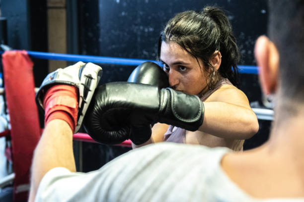istock Young woman training boxing with her trainer in the ring 1487831887