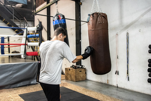 Young man training boxing with a punching bag at the gym