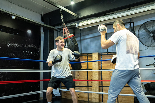 Young man training boxing with his trainer in the ring