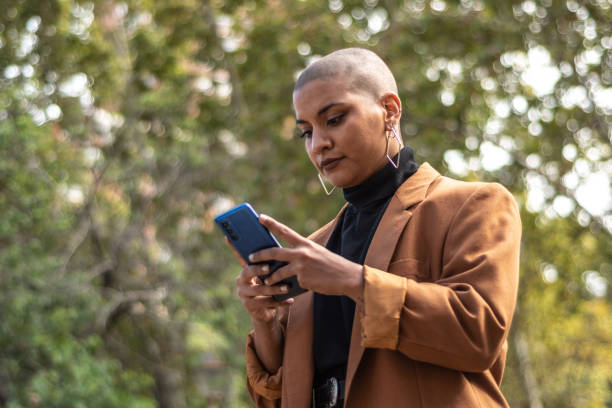 istock Young woman typing on mobile phone at public park 1487832924