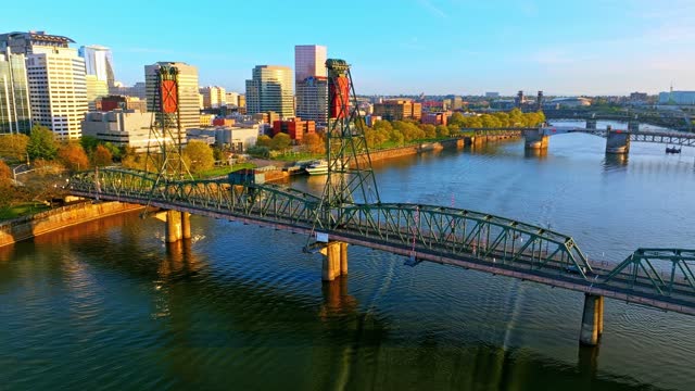 Portland Aerial: Golden Hour, Hawthorne Bridge, speeding boat, and Scenic Bridges & Moda Center in distance in Cityscape