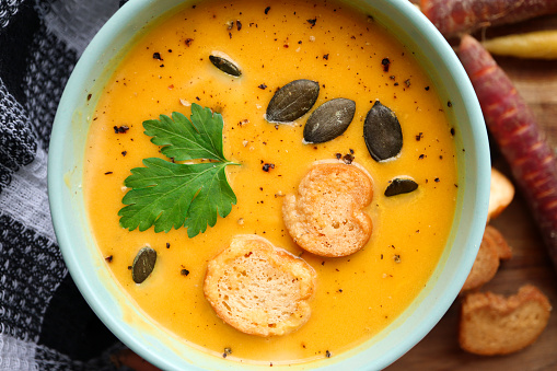 Bright yellow pumpkin, butternut and sweet potato soup with pumpkin seeds, croutons