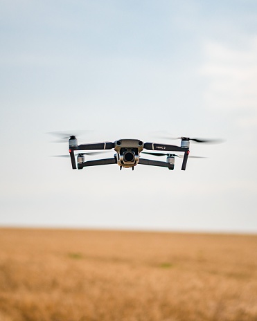 Szekesfehervar, Hungary – July 15, 2021: A modern drone takes flight over a vast expanse of golden wheat, highlighted by the sun