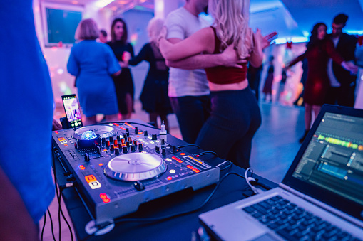 DJ playing and mixing music on the console for a salsa party indoors