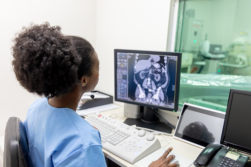 Radióloga negra mirando la tomografía computarizada de un paciente para escribir el informe en la clínica photo