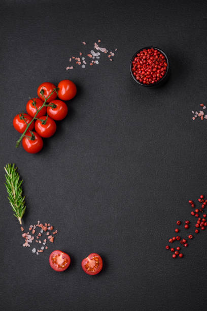 istock Empty black texture table, cherry tomatoes on a twig, spices, salt and herbs 1487838118