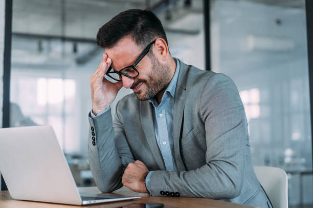 istock Stressed businessman having headache while working on laptop in the office. 1487838129