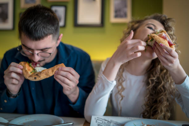 istock Playful couple eating pizza together in a restaurant 1487839027