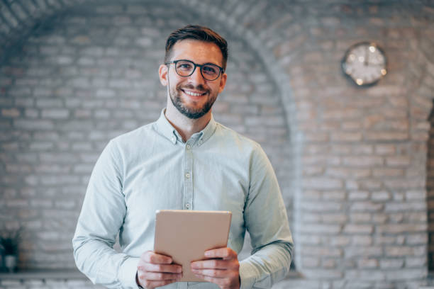 Make sure your business is portable. Shot of a handsome businessman using digital tablet in the office. sales executive stock pictures, royalty-free photos & images
