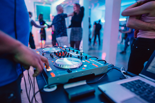 DJ playing and mixing music on the console for a salsa party indoors