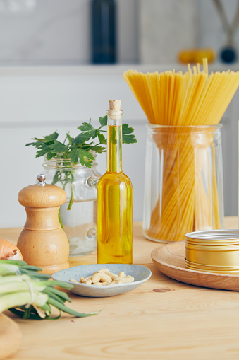 Raw pasta for food preparation, cooking, on a wooden kitchen or restaurant table, with fresh and dry seasoning, herbs and spices, parsley, olive oil, pumpkin seeds, representing gourmet indulgence and healthy lifestyle and city life, table top view with a copy space