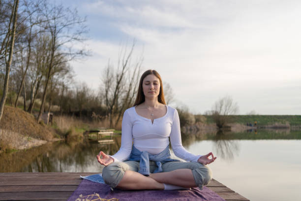 istock Woman relaxingly practicing meditation in nature by the lake. 1487841416