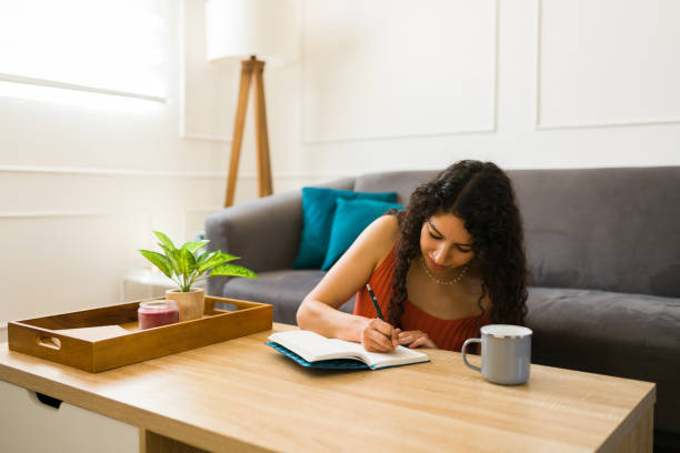 istock Latin young woman writing in her diary at home 1487843389