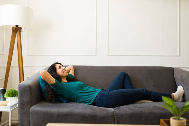 jeune femme se reposant et allongée sur le canapé du salon - lying on side audio photos et images de collection