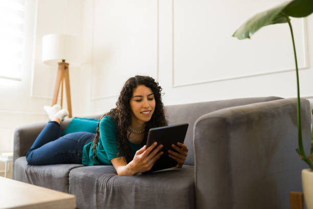 istock Relaxed happy woman lying on the sofa using a tablet 1487843524