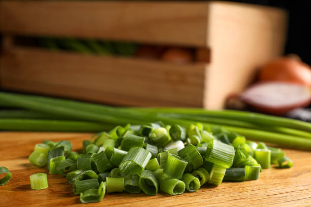 istock Chopped green spring onion on wooden board, closeup 1487844564