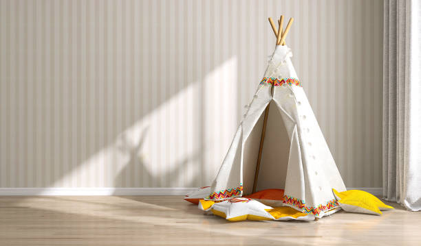 istock Cream fabric kid teepee tent, string light, cute red and yellow cushion pad in sunlight on cream white stripe wallpaper wall, parquet floor 1487845756