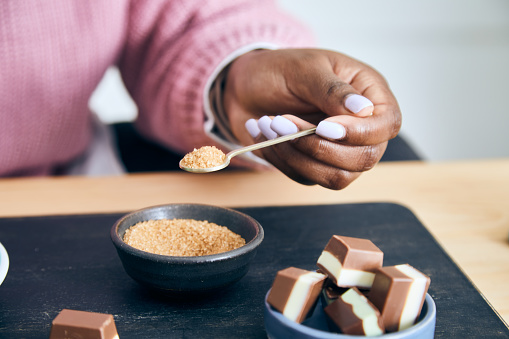 Portrait of a cute and happy young black girl in the kitchen, early bird morning routine, drinking coffee, with chocolate, representing positive mental attitude, wellbeing and a healthy lifestyle, an image with a large copy space