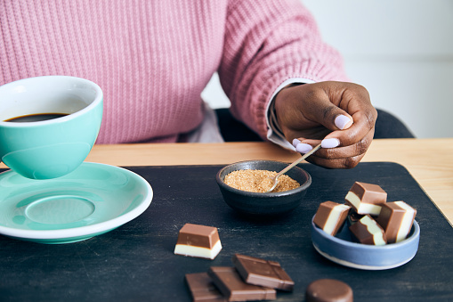 Portrait of a cute and happy young black girl in the kitchen, early bird morning routine, drinking coffee, with chocolate, representing positive mental attitude, wellbeing and a healthy lifestyle, an image with a large copy space