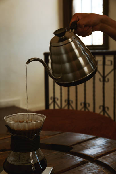 istock Barista pouring water from kettle into cup with coffee and wave dripper in cafe, closeup 1487849036