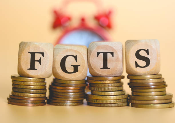 the acronym fgts written on wooden dice lying on piles of coins from brazil. alarm clock in the background in the composition. - retirement investment capital letter text imagens e fotografias de stock