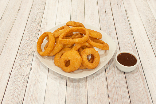 Great serving of American-style onion rings breaded and fried with barbecue sauce to dip