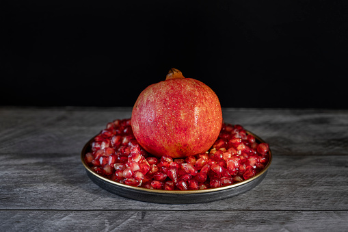 One red pomegranate on red ripe pomegranate grains on vintage metal plate