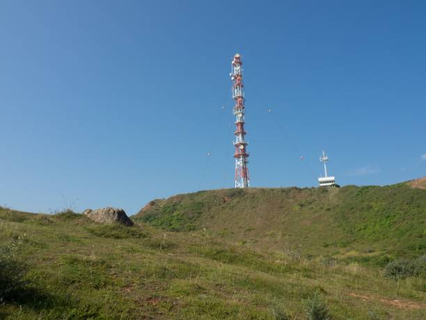 istock Cellular tower standing atop a hill surrounded by a blue sky 1487854619
