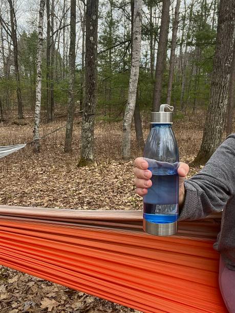 istock Partial view of woman holding plastic refillable water bottle in her hammock. 1487856353