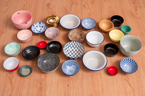Set of empty bowls of different textures and colors on oak background