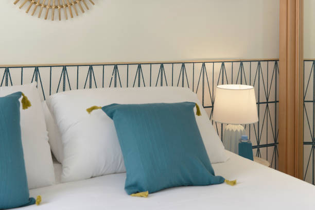 istock Double bedroom with white pillows, blue cushions, wall with wallpaper and mirrors 1487856608