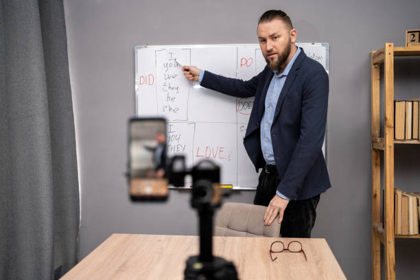 istock Young man english teacher calling on smartphone, having video conference, talk by webcam teaching in online chat at home. Remote classroom concept. 1487860018