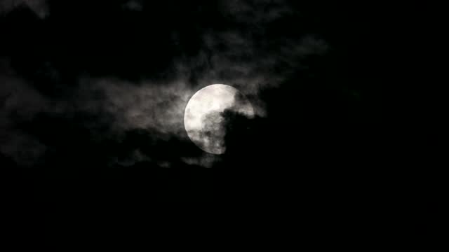 The full moon partially covered with the moving clouds