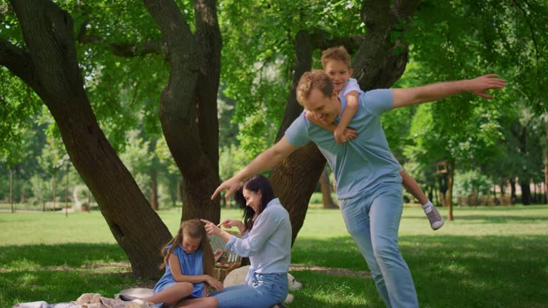 Little son have piggyback ride on happy father. Agile man hold cute boy on back.