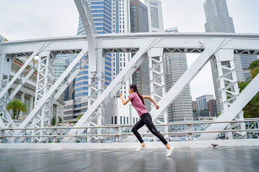 asian sports woman running on Anderson Bridge in Singapore city
