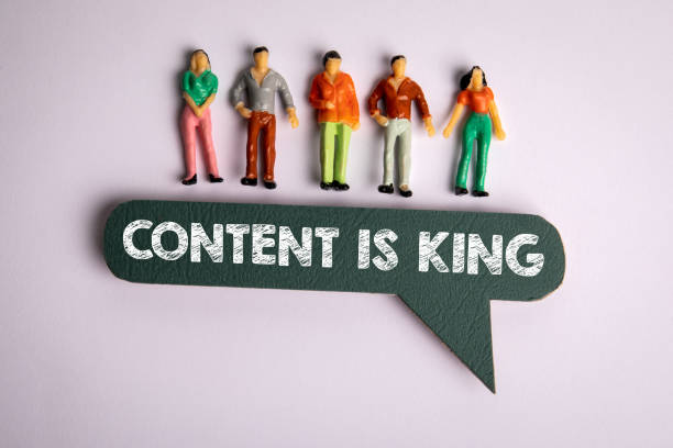 CONTENT IS KING CONCEPT. Miniature human figures and speech bubble on a white background stock photo