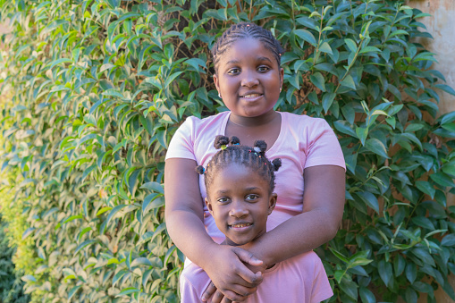 Portrait of happy afro-american little sisters smiling  together at outdoor garden background