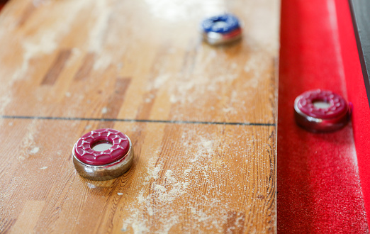 Shuffleboard is a game of precision and strategy, where players slide weighted discs down a narrow court to reach scoring areas. The sport represents the pursuit of accuracy and patience