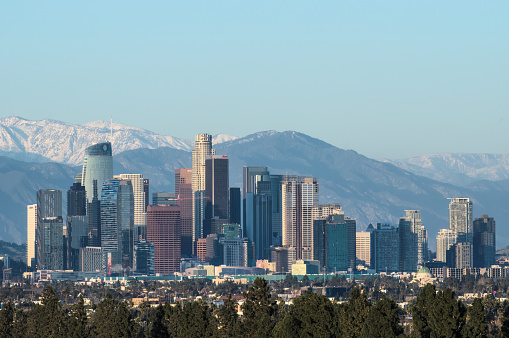 Los Angeles, California, United States - March 25, 2023: downtown Los Angeles telephoto image, facing southwest, shown at dusk with the San Gabriel Mountains in the background.