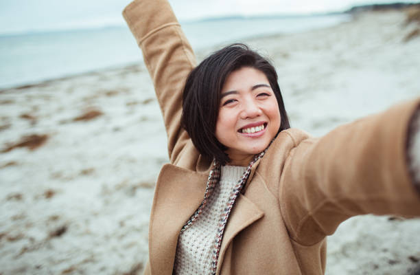 istock Young Asian woman taking a selfie on a beach 1487878458