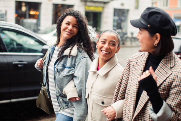 istock Three young women walking down a street in a town 1487878656