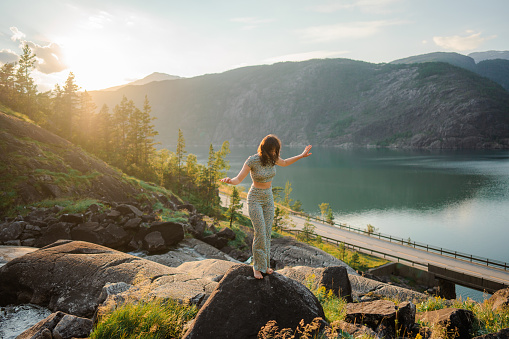 Young Caucasian woman standing  near the waterfall and looking at fjord in Norway