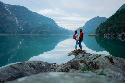 Young Caucasian man and woman standing near the highland lake in Norway