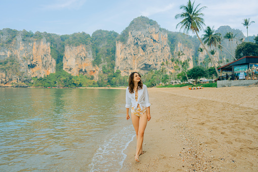 Young Caucasian woman  walking on Railey beach and looking at stunning scenery